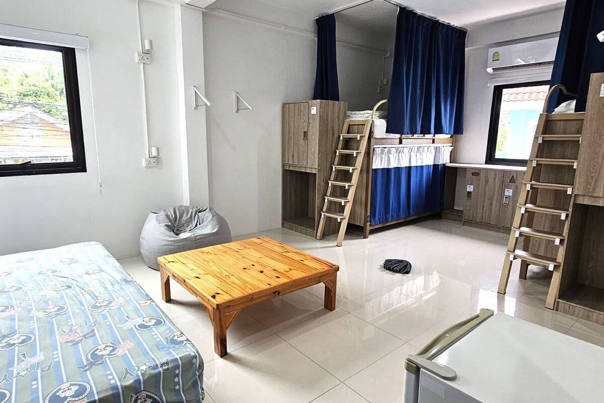 A compact room with a bunk bed, a small table, a bean bag, and a window with a view of a bridge.