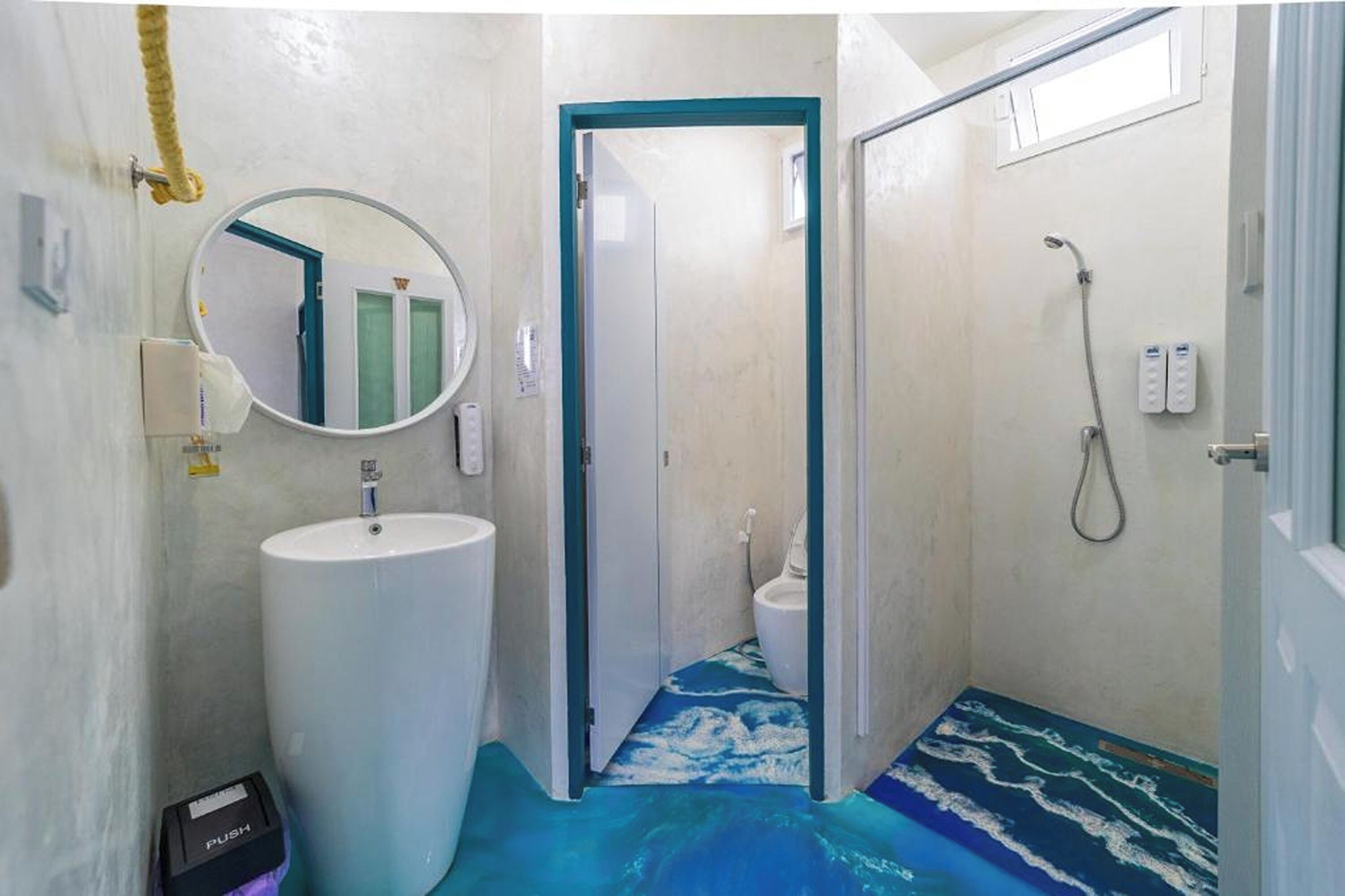 A bathroom with a large sink, a mirror, a shower, and a door leading to another room.