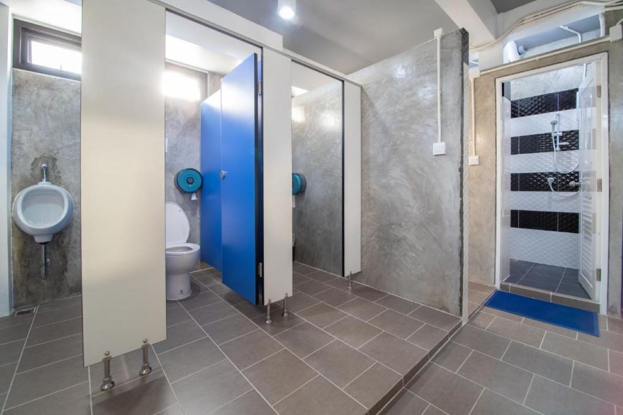 A modern bathroom with a urinal, toilet, and shower stall.