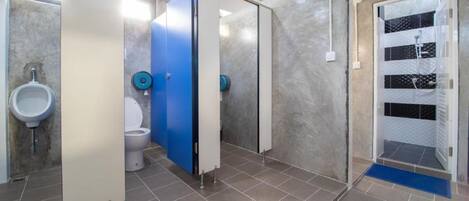 A modern bathroom with a urinal, toilet, and shower stall.