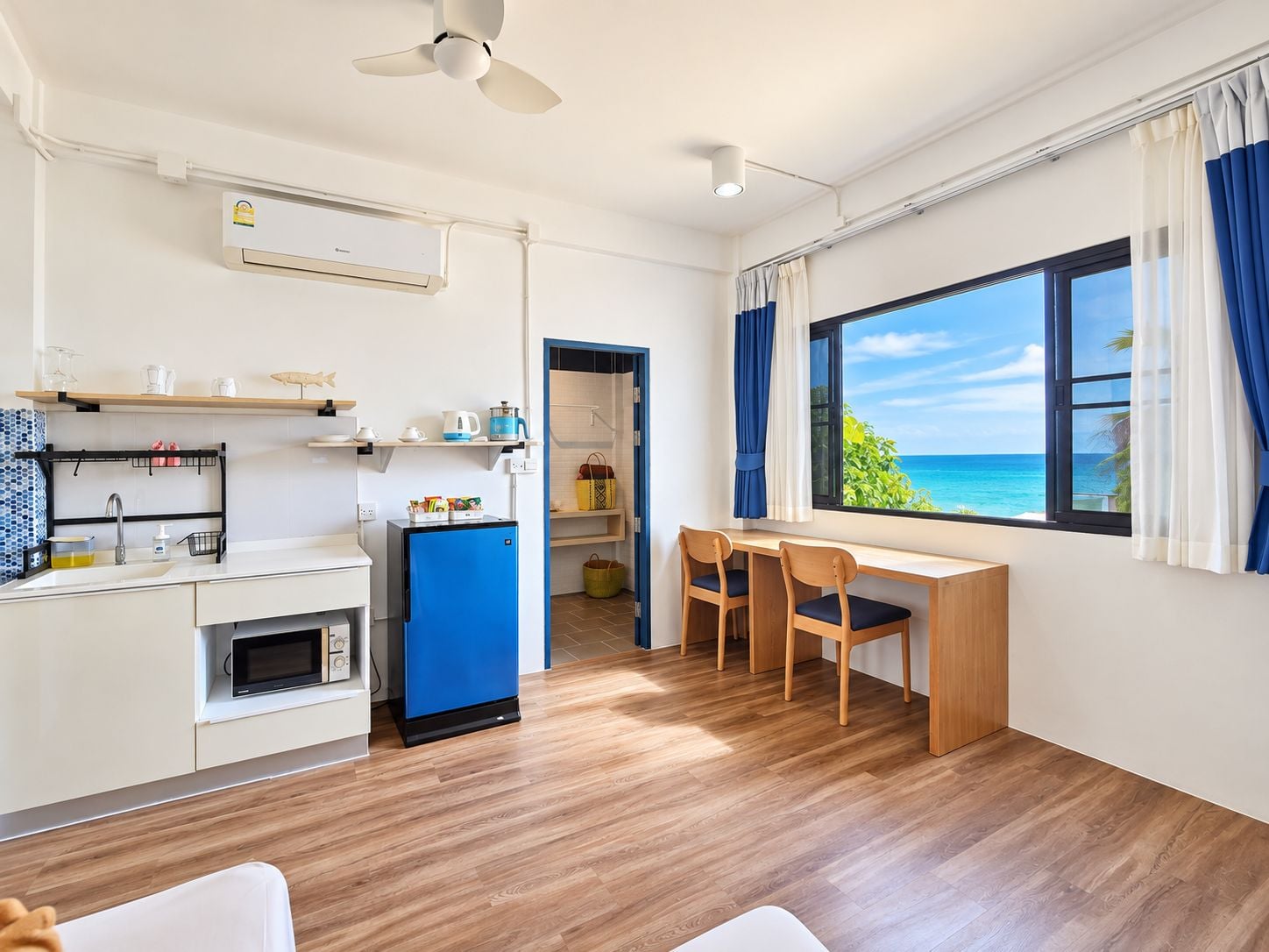 Cocina compacta con microondas, refrigerador y un comedor con sillas y mesa.