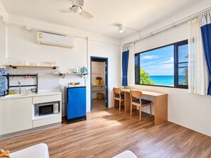 A compact kitchen with a microwave, refrigerator, and a dining area with chairs and a table. - The Rock Samui Poshtel Lamai Beach (Koh Samui)