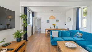 Un salon moderne avec un canapé bleu, une table basse en bois et un coin repas comprenant une table et des chaises en bois.