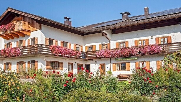 Un edificio de dos pisos con balcones decorados con flores, fachada blanca y marcos de ventanas de madera.