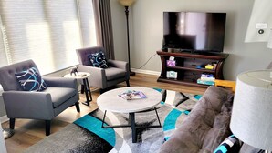 A living room with a sofa, armchair, coffee table, TV, and a lamp. - 4 Bedroom, 2 Full Bath. Centrally Located. Near O'Hare Airport and attractions   (Glenview)