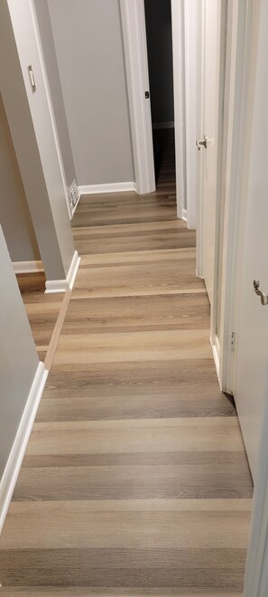 Un pasillo con suelo de madera y paredes blancas.