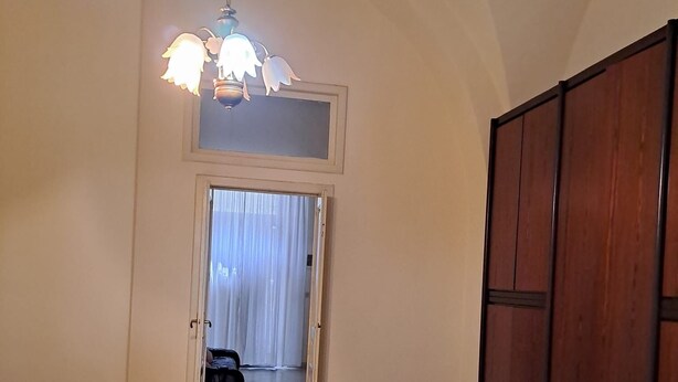 Ein Zimmer mit Fliesenboden, einem Bett, einem Kleiderschrank und einer Tür zu einem anderen Raum.