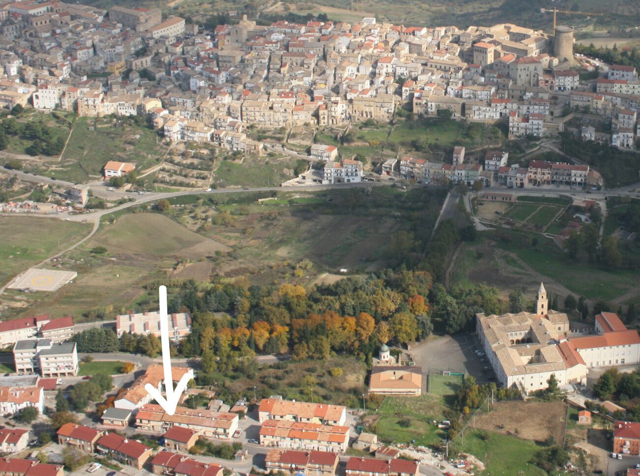 An aerial view of a town with a prominent church, surrounded by residential buildings and green spaces.