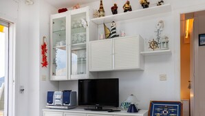 Een woonkamer met een televisie, kasten en decoratieve objecten.