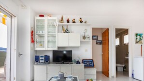 Een functioneel woongedeelte met een eethoek, televisie en keuken.