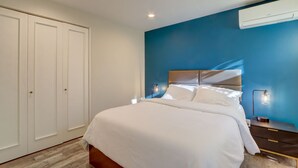A bedroom with a bed, bedside lamps, a nightstand, and a wardrobe.