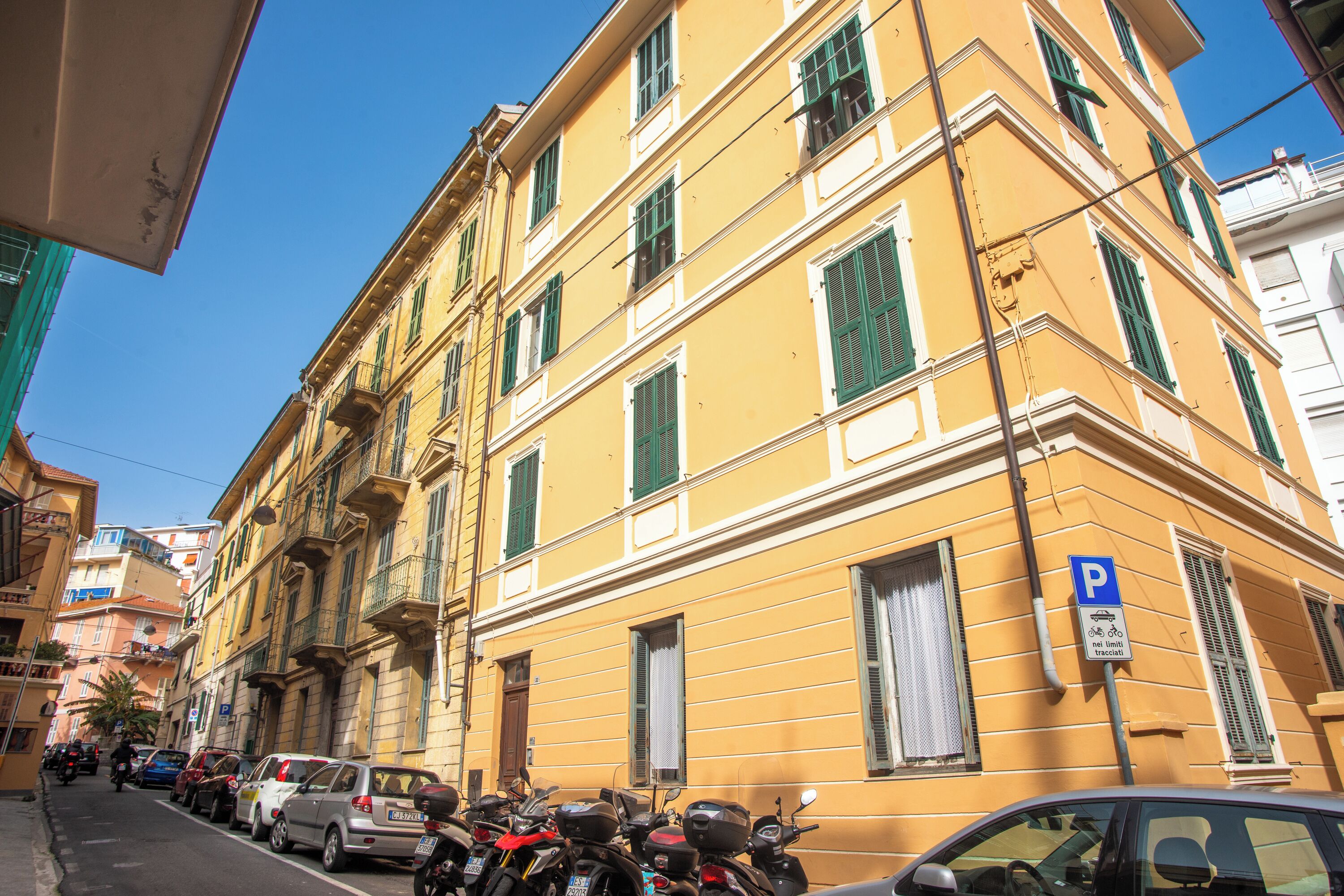 Un bâtiment jaune avec de nombreuses fenêtres et un panneau indiquant un parking.