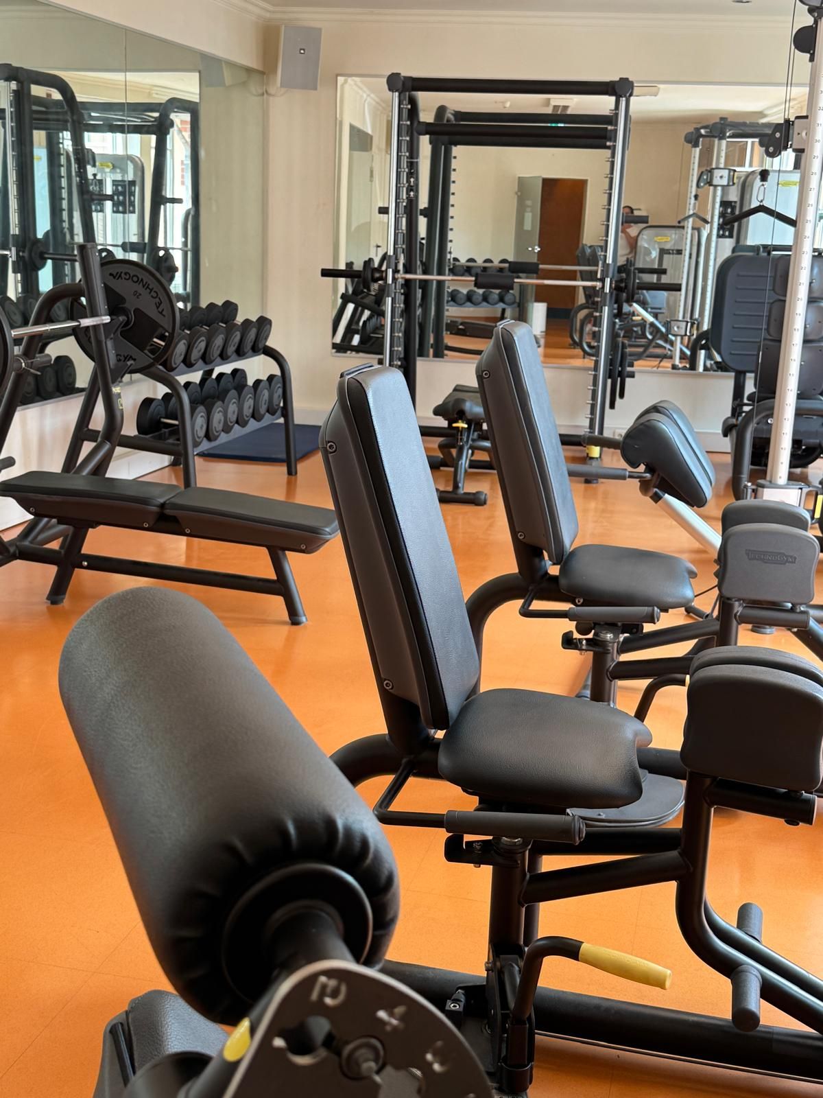 Un gimnasio con equipamiento de ejercicio, incluyendo bancos y máquinas de pesas.