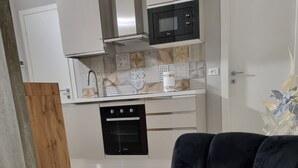 A modern kitchen with a microwave, oven, and white cabinets. - CÀ Fiamma 2 Affitti Brevi (Casale Monferrato)