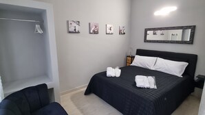 A bedroom with a bed, a chair, a wardrobe, and four wall-mounted pictures. - CÀ Fiamma 2 Affitti Brevi (Casale Monferrato)