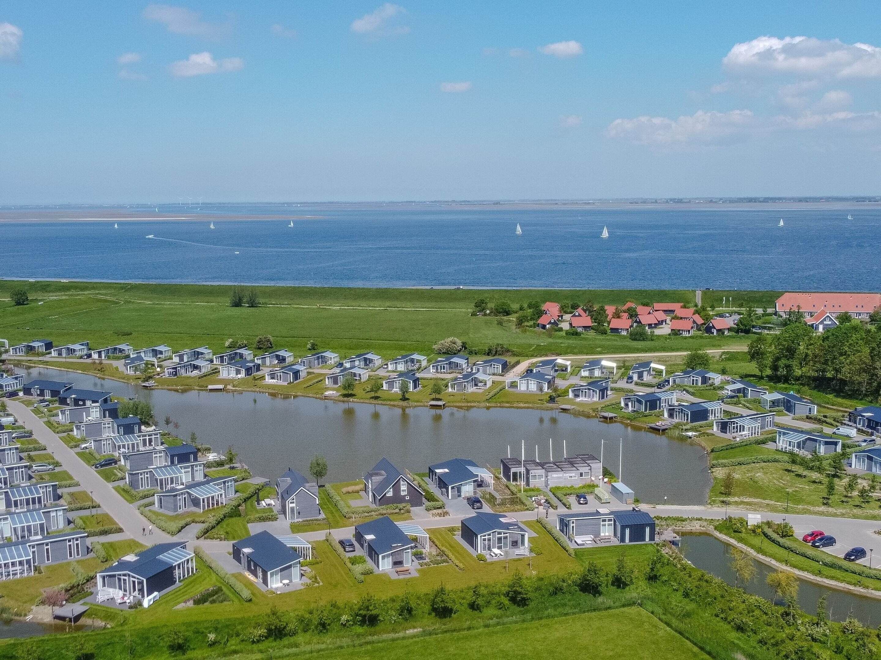 A coastal residential area with modern houses, a lake, and sailboats on the water.