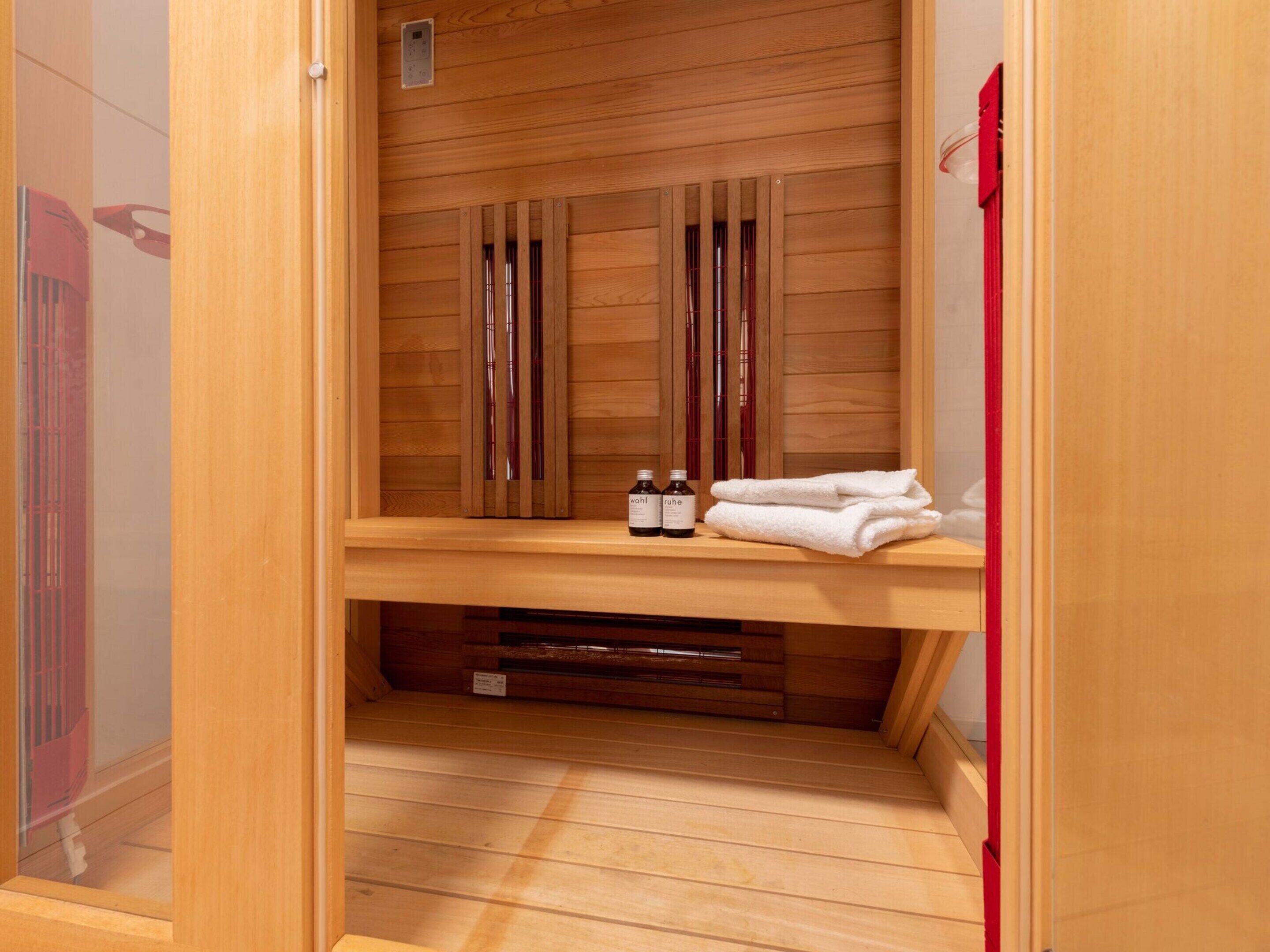 A wooden sauna with a bench, a shelf with bottles, and a towel.