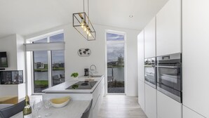 Een moderne keuken met een groot eiland, ingebouwde apparatuur en uitzicht op een waterpartij.