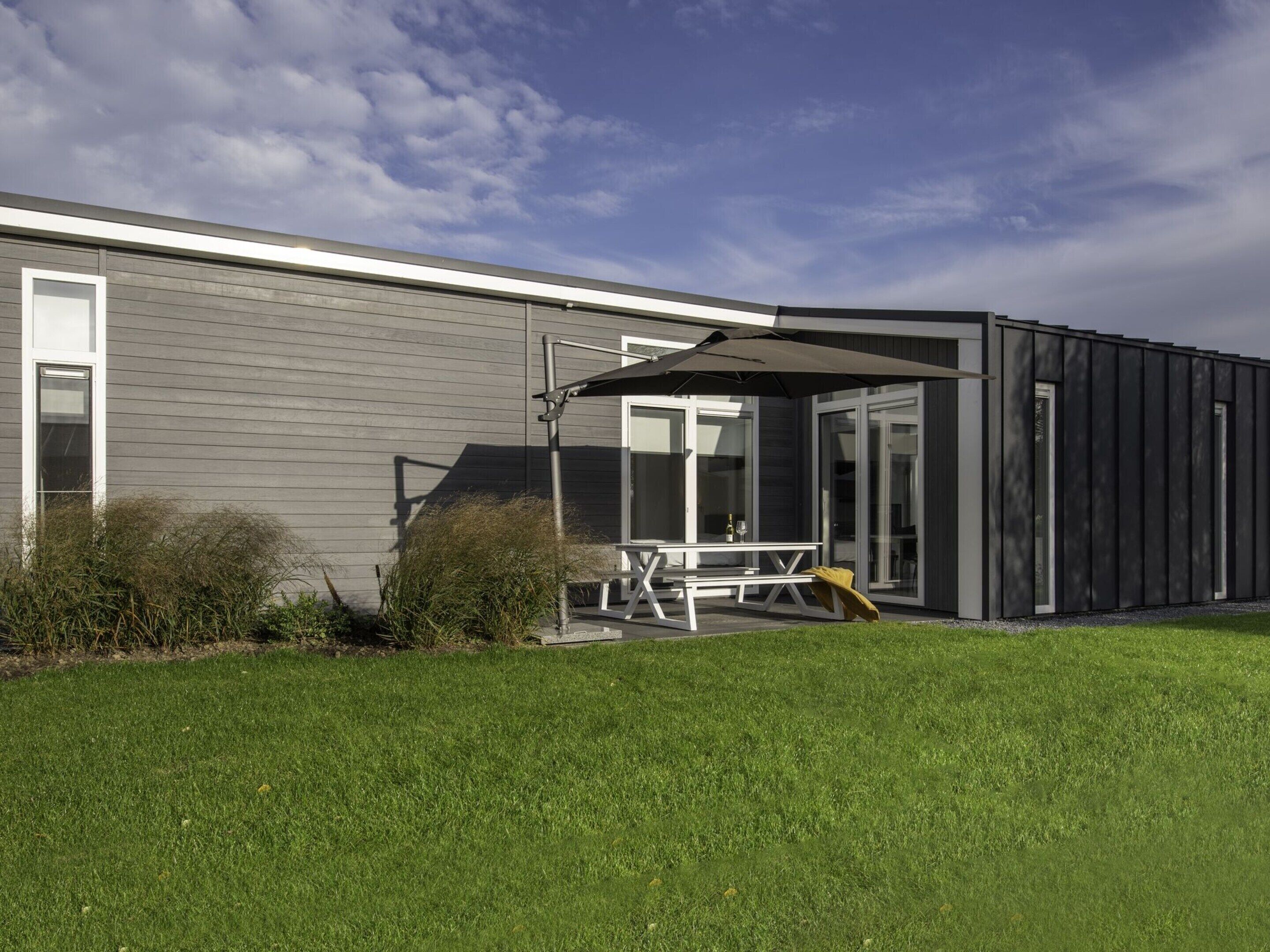 A modern building with a patio area featuring a table and chairs, and a covered seating area.