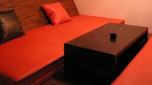 A room with a wooden headboard, a red sofa, a small wooden table, and a red curtain. - Hip Spa Motel (Taichung)