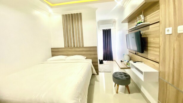 Una habitación de hotel con cama, escritorio, televisor y estante en la pared.