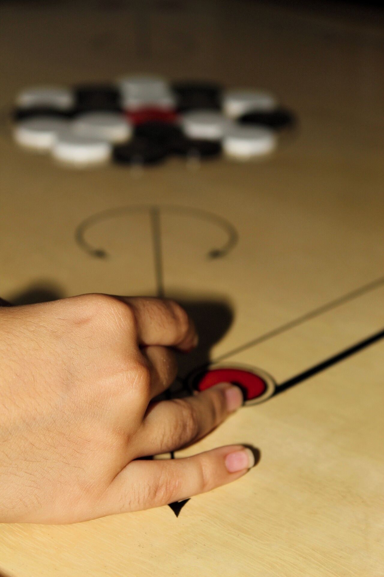 Eine Hand, die einen Stift hält und bereit ist, auf einer Holzfläche zu schreiben, mit einem roten und schwarzen Gegenstand im Hintergrund.