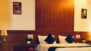 Une chambre d’hôtel avec un grand lit, une table de chevet avec une lampe, une petite plante et des œuvres d’art accrochées aux murs.