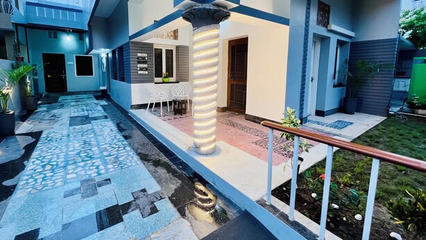 Un bâtiment moderne doté d’une allée dallée, d’une colonne centrale et d’un petit espace extérieur aménagé pour s’asseoir.