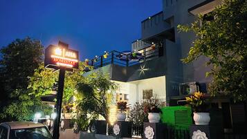 Un bâtiment moderne avec une enseigne indiquant « AHA HOMESTAY » et des balcons décorés de guirlandes lumineuses.