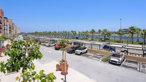 Un parking avec plusieurs voitures, un chemin piétonnier et des palmiers.