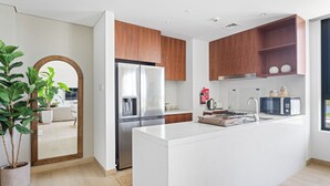 Une cuisine moderne dotée d’un îlot central, d’appareils électroménagers en acier inoxydable, de meubles en bois et d’un grand miroir.