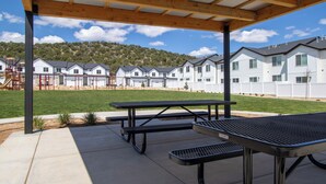 An outdoor patio area with picnic tables and a playground in the background.