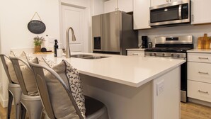 A modern kitchen with white cabinetry, stainless steel appliances, and a central island.