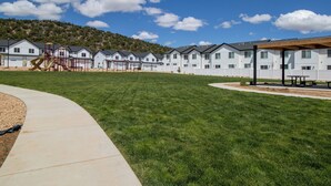 A residential area with a row of white houses, a playground, and a covered seating area.