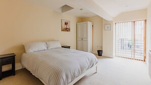Un dormitorio con cama, mesitas de noche, un armario y una ventana con persianas.