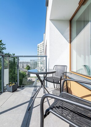 Enjoy the city view from this balcony with a table for two and a potted plant.