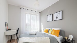 A bedroom with a bed, a desk, and a chair. There are two framed pictures on the wall. - Apartament Ludwiki (Warsaw)
