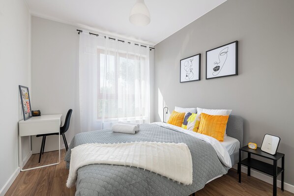 Cozy retreat with a bed, nightstand, and desk, offering a peaceful space to unwind.