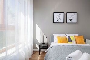 Relax in a serene space with a neatly made bed, bedside table, and wall-mounted artwork.