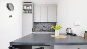 A modern kitchen with a grey countertop, a built-in stove, and a white vase with yellow flowers. - Apartament Ludwiki (Warsaw)