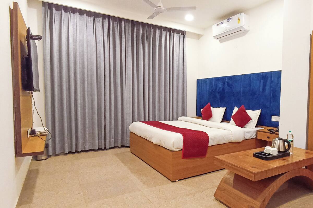 A hotel room with a bed, a wooden nightstand, a desk, and a wardrobe.