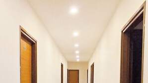 Un pasillo largo y estrecho con suelo de baldosas y puertas a ambos lados que dan a habitaciones.