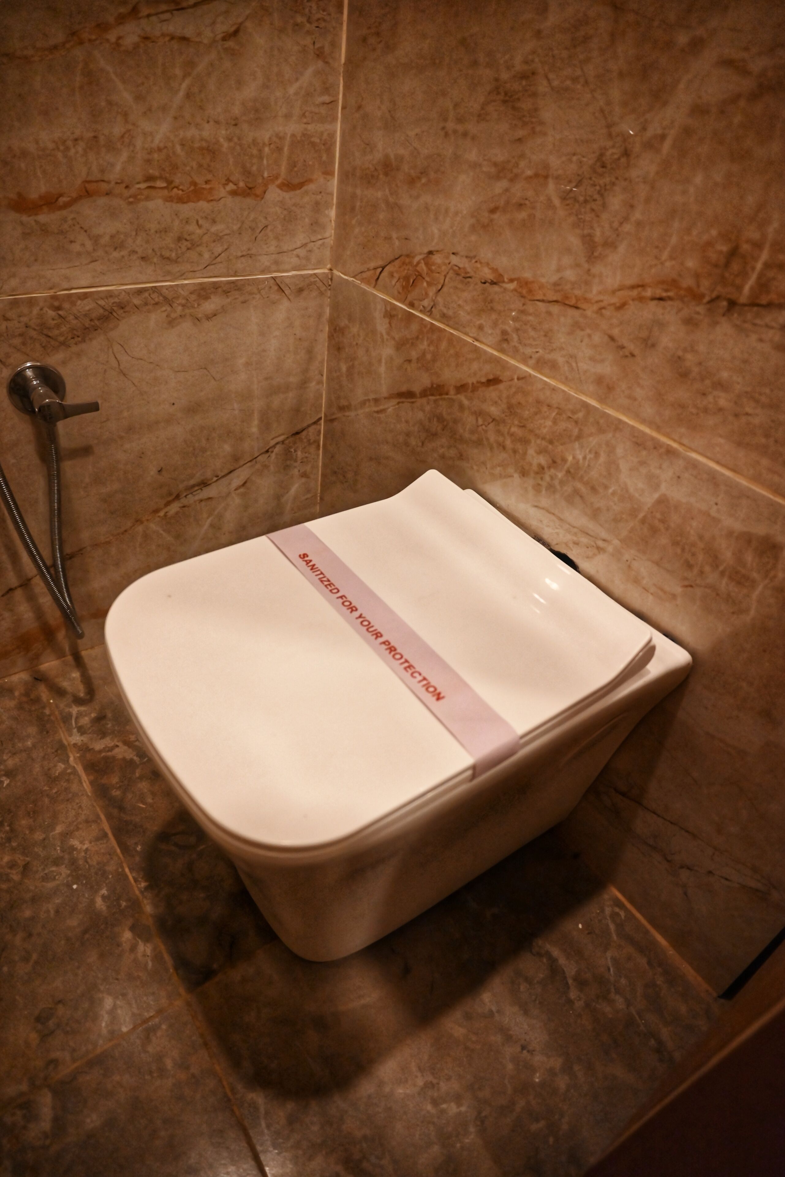 Un baño con inodoro, ducha y suelo de mármol.