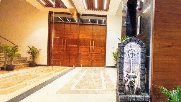 Un vestíbulo moderno con piso de mármol, puertas de madera y una fuente de piedra.