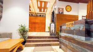 Zona de recepción con un mostrador de madera, un sofá y una escalera que lleva a un piso superior.