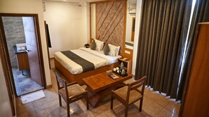 Una habitación de hotel moderna con cama, mesita de noche y escritorio con sillas.