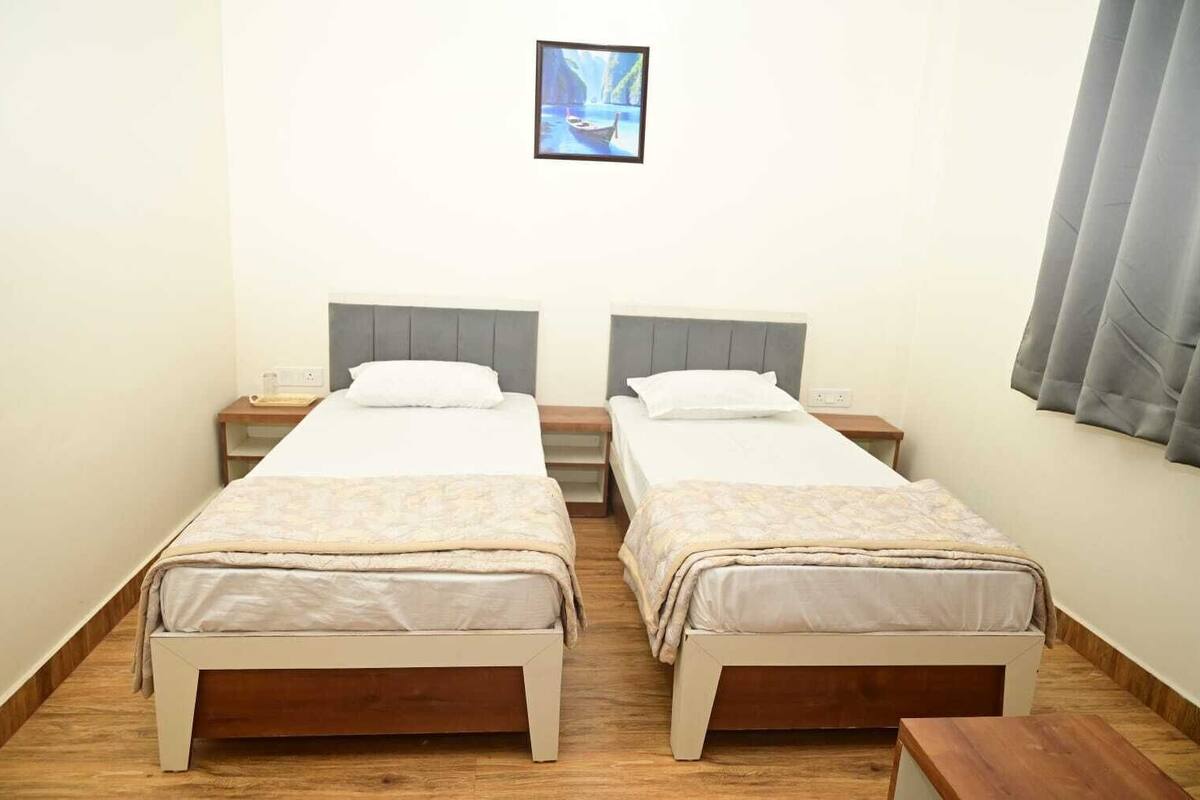 A double room with two single beds, wooden floors, and a framed picture on the wall.