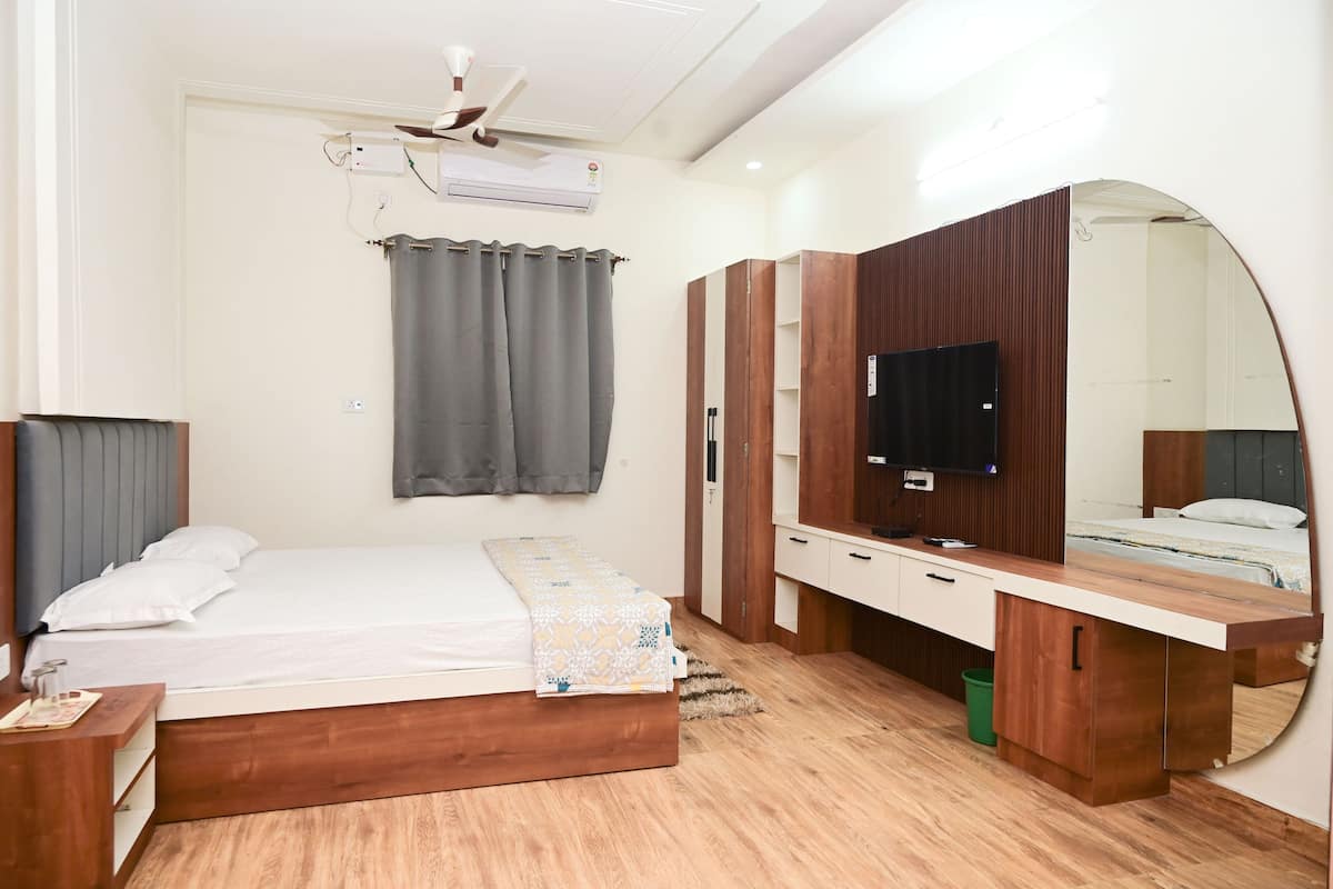 A modern bedroom with a bed, a vanity with a mirror, a ceiling fan, and a TV.