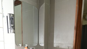 A bathroom with a white sink, a mirror, and a wooden cabinet. - Green Park (Varanasi)