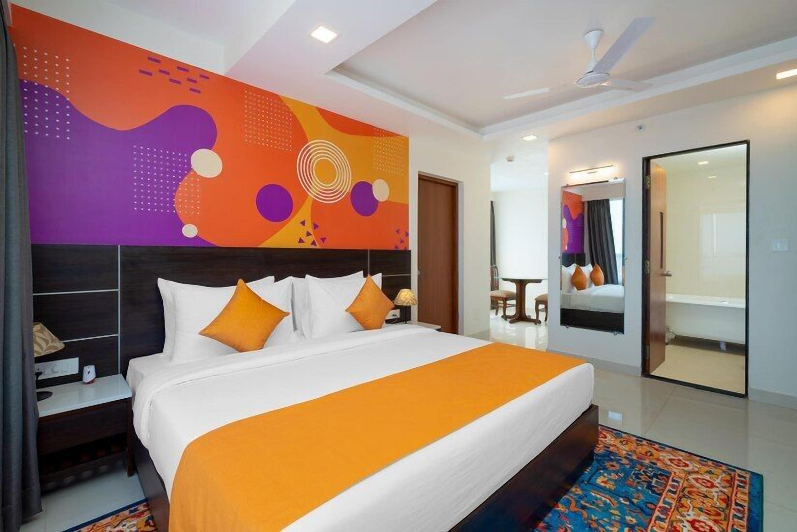 A hotel room with a large bed, a nightstand, a mirror, and a modern wall design.